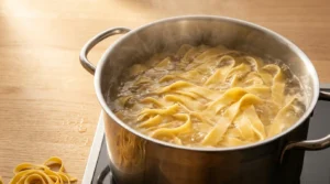 Egg noodles boiling in a separate pot of salted water, prepared for chicken soup recipe.